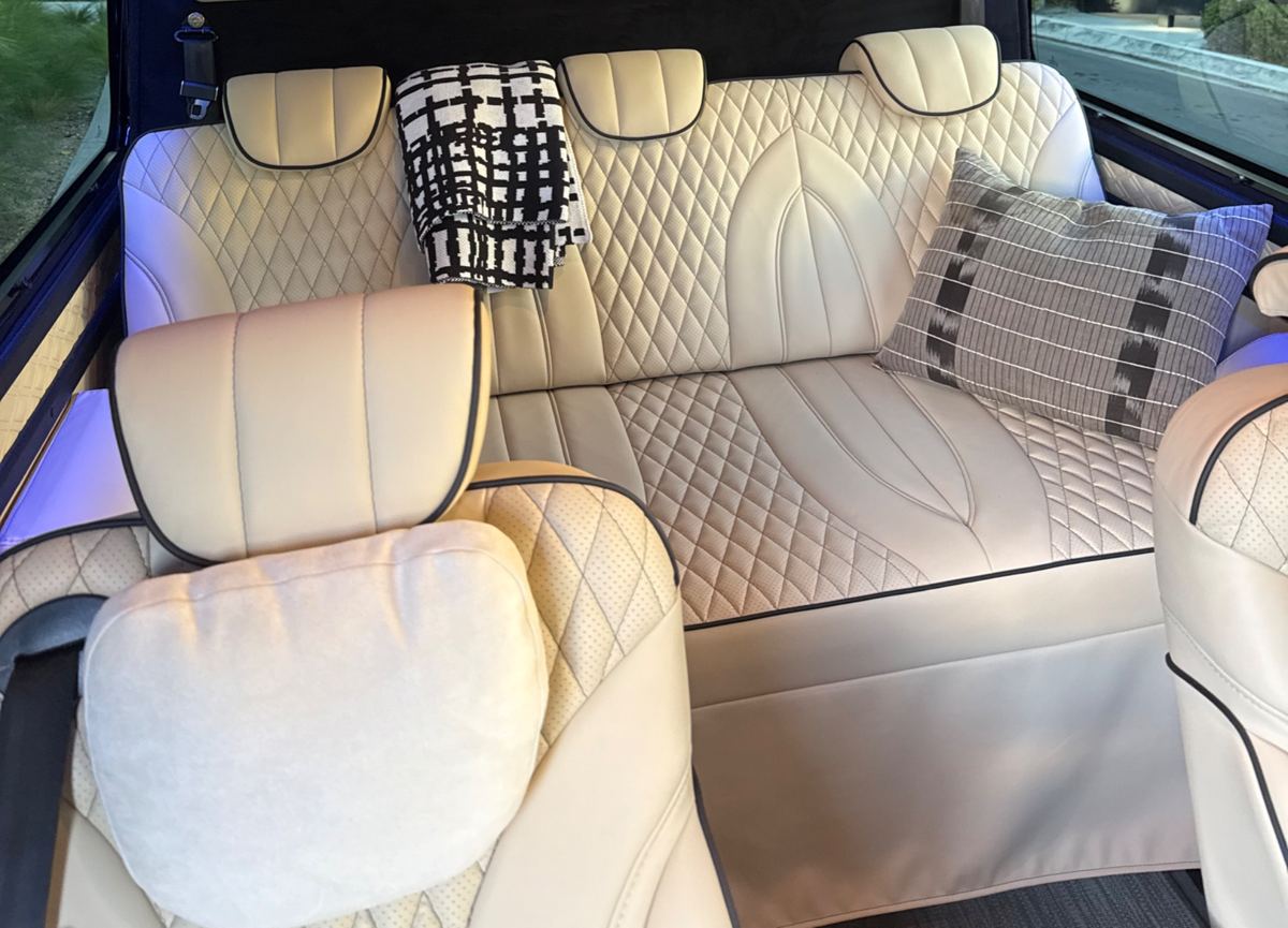 The cabin's rear bench in quilted ivory leather with a throw and pillow